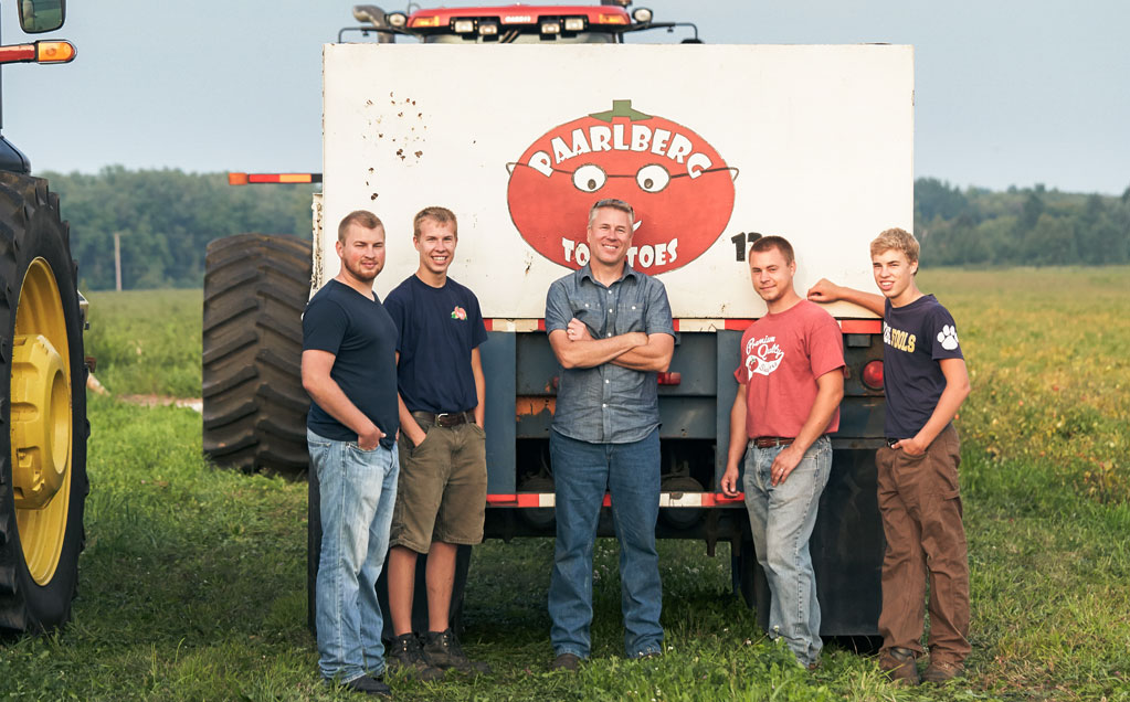 Iimage of Paarlberg Farms with Jim and sons standing at the back of a load of tomatoes in a tomato field
