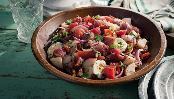 Confetti Potato Salad Image of Confetti Potato Salad in wooden bowl with sliced eggs sliced onion and diced tomatoes