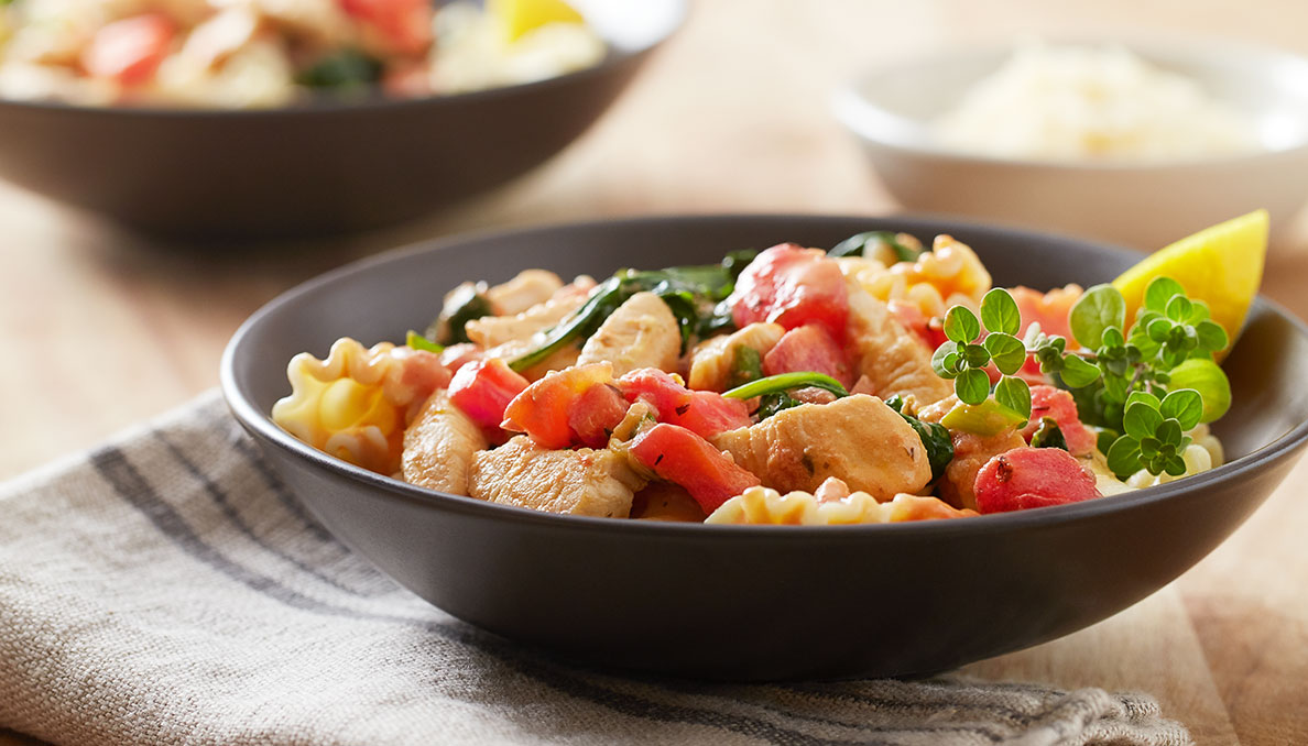 RG_Web_Chicken-Florentine-Pasta Image of Red Gold Creamy Chicken Florentine Pasta in black bowl with tomatoes and herbs