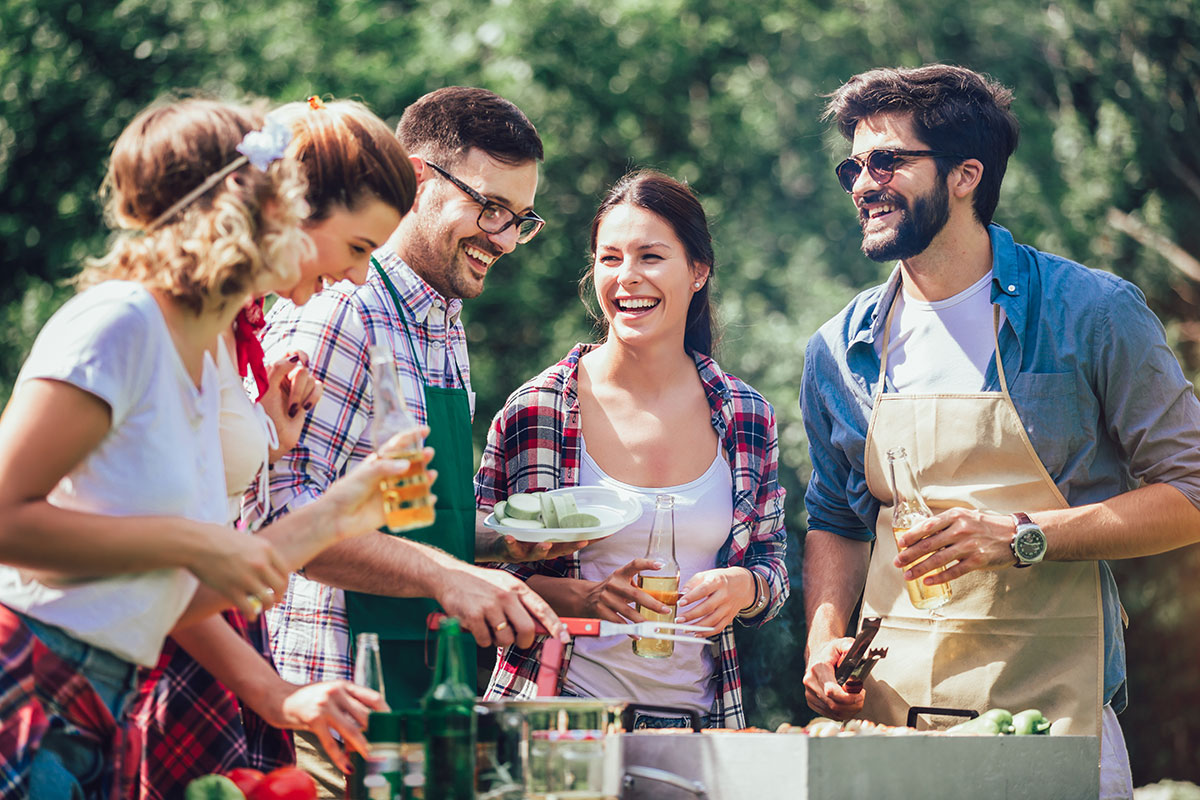 Image of young adults hanging out at campsite with cooler